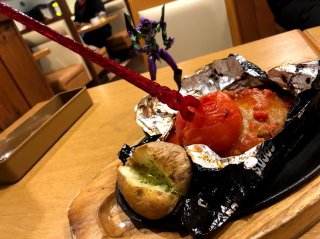 「コア包み焼きハンバーグ」（税込み・1859円）のロンギヌスの槍に驚くミニ初号機さん／（Ｃ）コクハク